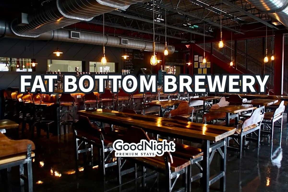 Inside a lively, modern bar with a long wooden counter, inviting hanging lights, and a relaxed seating area. The atmosphere is social and welcoming, perfect for starting an evening out or recapping adventures with friends.
