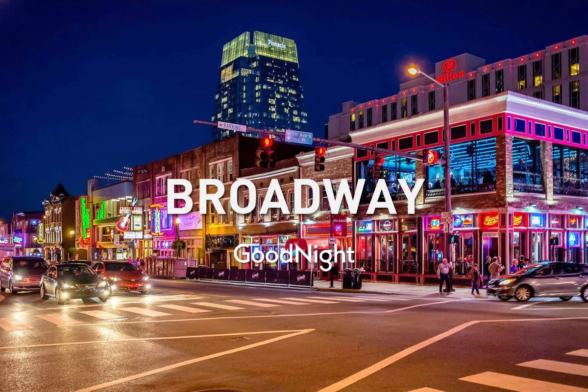 A nighttime streetscape featuring neon signs, bustling pedestrians, and vibrant street life. High-rise buildings glow in the background, and the scene radiates the energy of Nashville’s nightlife district, hinting at live music venues and lively dining experiences.